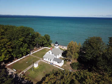 aerial view of Mission Point Lighthouse looking out towards bay and blue sky horizon