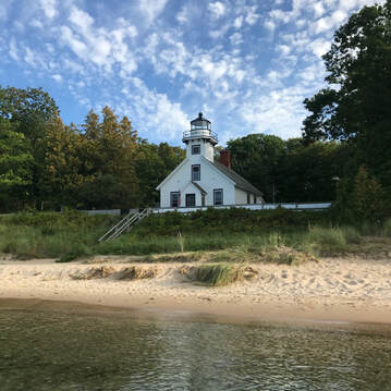 View of white lighthouse and beach from water